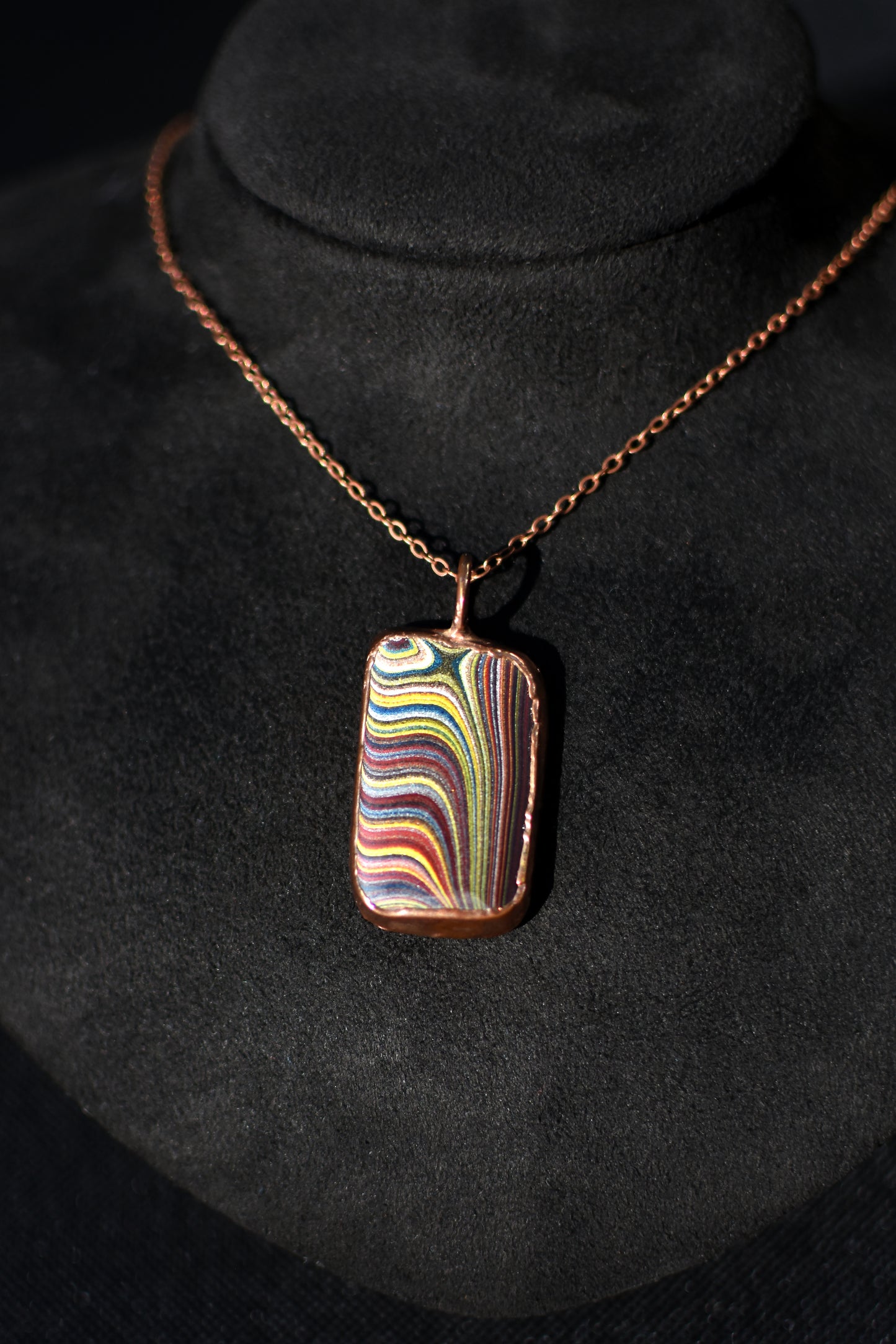 Necklace with a colorful Fordite pendant on a black background